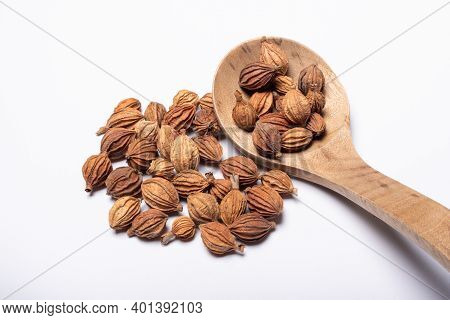 Heap Of Amomum Villosum Lour Dried Fruit With A Wooden Spoon On A White Background Close-up View