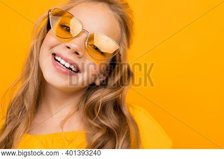 Portrait Of Young Caucaian Girl With Long Fair Hair In Yellow Glasses Smiles