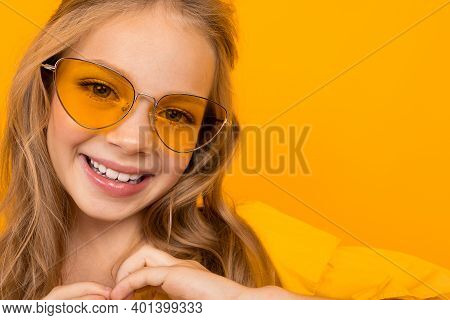 Portrait Of Young Caucaian Girl With Long Fair Hair In Yellow Glasses Smiles