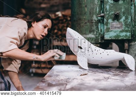 Portrait Of Young Woman Carefully Work On A Ceramic Whale In Workshop.