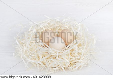 Raw Organic Brown And White Eggs In Nest Made Of Staw Shreded Paper.