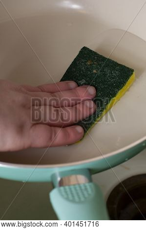 Woman Washing A Frying Pan With A Scrubbing Sponge