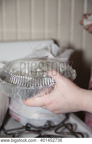 Woman Holding A Carryout Tin In Front Of A Carryout Bag Filled With Food