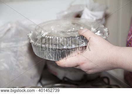 Woman Holding A Carryout Tin In Front Of A Carryout Bag Filled With Food