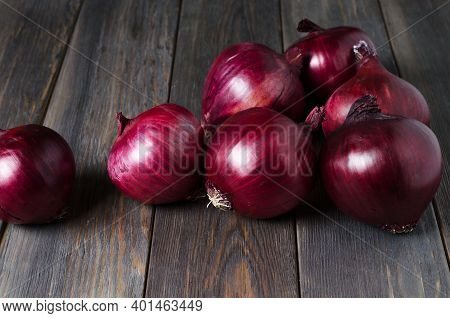 Lots Of Red Onions On A Brown Wooden Background.