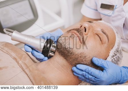 Cropped Shot Of A Professional Cosmetologist Doing Rf-lifting Treatment For Mature Male Client. Rela