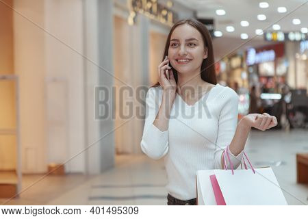 Stunning Cheerful Female Customer Walking At The Mall, Talking On Her Phone, Carrying Shopping Bags,