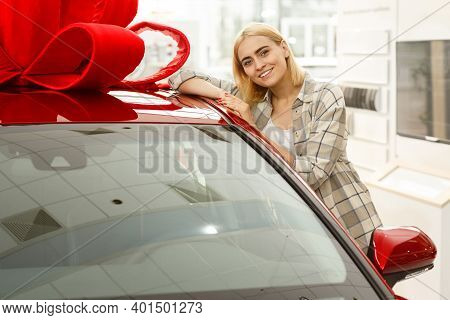 Attractive Young Happy Woman Smiling Cheerfully To The Camera Leaning On Her New Automobile At The D