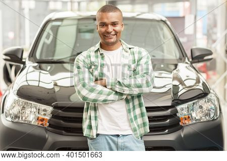 Portrait Of A Happy Handsome Male Driver Posing In Front Of His Newly Bought Automobile At The Deale