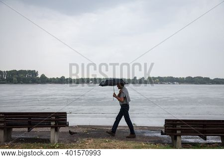 Belgrade, Serbia - July 2, 2017: Old Man Walking With And Umbrella Near The Danube River During A He