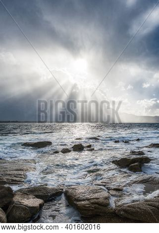 Sun Rays Burst Through Storm Clouds Over Calvi In The Balagne Region Of Corsica With The Rocky Medit