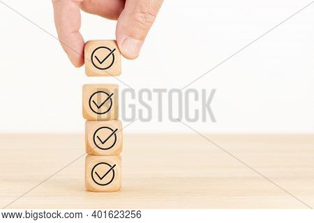 Checking Or Checklist Concept. Hand Picked Wooden Cube Block With Check Icon Stacked On Wooden Table