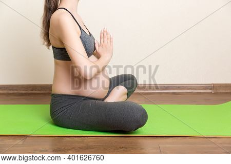 Beautiful Young Pregnant Woman Sitting On Mat In Yoga Pose At The Home. Pregnancy Yoga And Fitness C