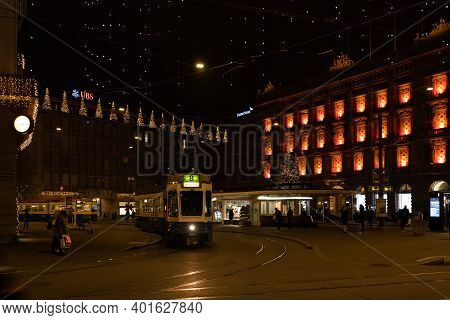 Paradeplatz At Christmastime At Night. Illuminated Windows Of Headquarter Of Banks And Tram Station 