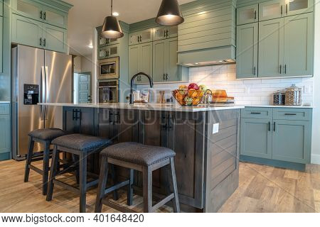 Kitchen Island With Stools Against Cabinets Refrigerator And Cooktop Background