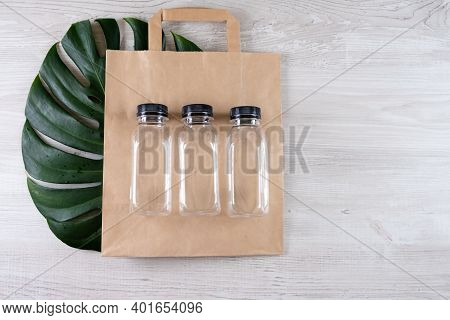 Three Plastic Bottles On A Brown Paper Eco Bag. Place For Your Logo. Eco-friendly Food Packaging And