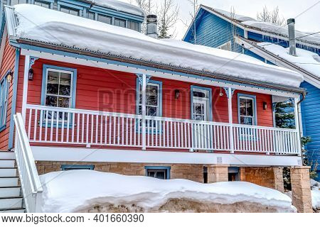 House With Red Wall And Stairs Going Up To Front Deck With White Post Railing