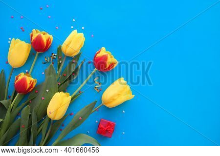 Bouquet Of Yellow And Red Tulips And Small Hearts On A Blue Background. International Women Is Day -