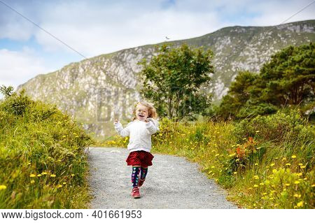 Cute Little Happy Toddler Girl Running On Nature Path In Glenveagh National Park In Ireland. Smiling