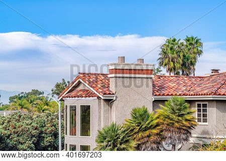 House Exterior With Tile Roof Bow Bay Window And Chimney Against Clouds And Sky
