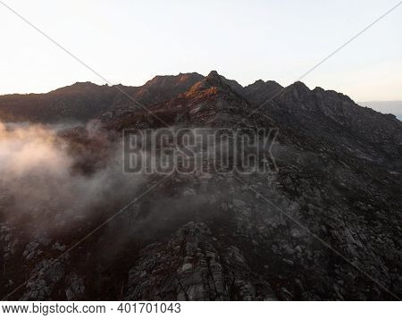 Aerial Sunrise Panorama Of Rolling Clouds Incoming Rock Mountain Hill At Cascada De Ezaro Waterfall 