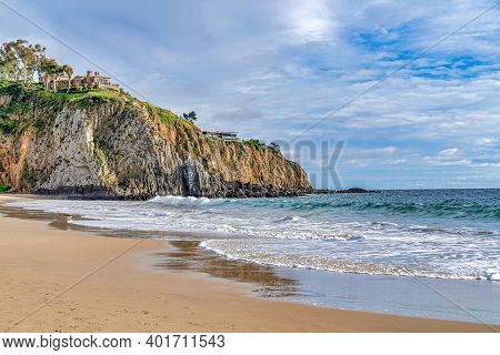 Shore And Ocean By A Rocky Cliff Against Cloudy Sky In Laguna Beach California
