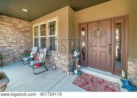 Brown Front Door And Sidelights At The Facade Of Home With Bench Against Window