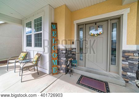 Gray Front Door With Sidelights Of A Home With Chairs At The Concrete Open Porch