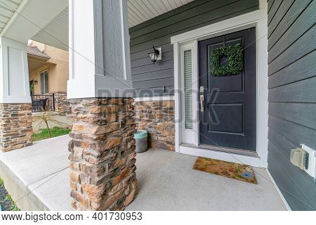 Home Facade With Open Porch And Gray Front Door Decorated With Green Wreath