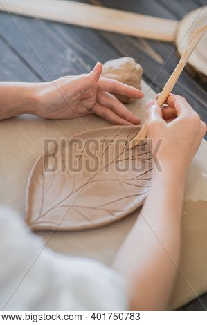 Female Potters Hand Making Clay Pottery At The Table With A Different Wooden Tools Close Up.