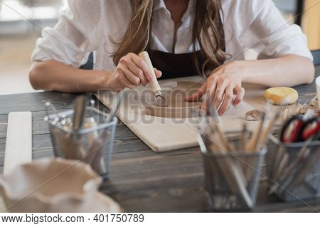 Female Potters Hand Making Clay Pottery At The Table With A Different Wooden Tools Close Up.