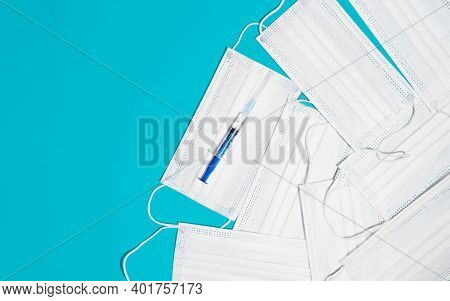 Syringe And Many Medical Face Masks, Top View. Concept For Midicine And Healthcare, Vaccination.