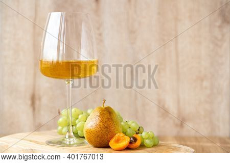 Amber Or White Wine With Fruit. Poured Glass With Wine Surrounded By Grapes, Peaches And Pears On A 