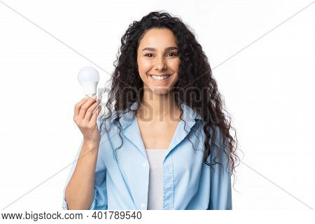 Happy Woman Showing Energy-saving Light Bulb Posing Standing In Studio On White Background, Smiling 