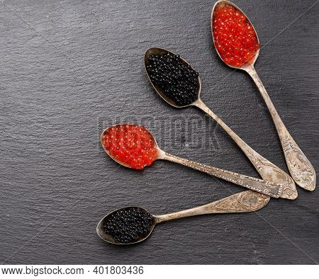 Black Caviar Of Paddlefish Fish And Red Chum Salmon Caviar In A Spoon, Black Background, Top View
