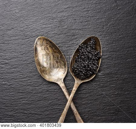 Black Caviar Of Paddlefish Fish In A Spoon, Black Background, Top View