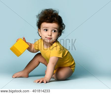 Small Cute Smiling Curly Hairy Baby Boy Toddler In Yellow Comfortable Jumpsuit Sitting On Floor With