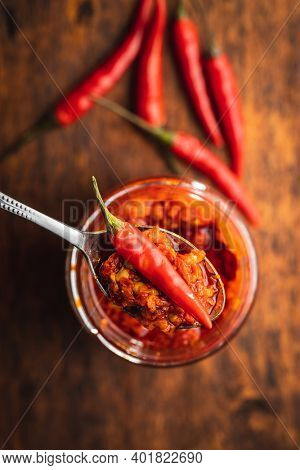 Red hot chili paste and chili pepper on spoon. Top view.