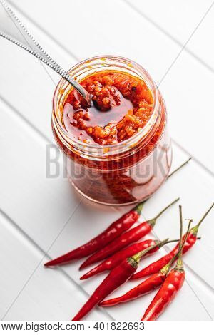 Red hot chili paste and chili pepper on white table.