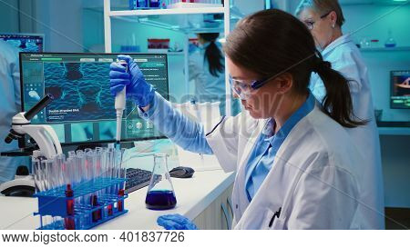 Chemist Putting Liquid In Test Tube With Micropipette In Modern Equipped Laboratory. Multiethnic Tea