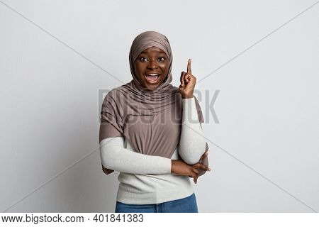 Excited Black Islamic Lady In Headscarf Having Idea, Pointing Finger Up, Emotional Africam Muslim Wo