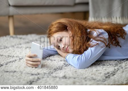 Spending Time At Home. Portrait Of Cal Smiling Red-haired Genz Tween Girl Using Her Mobile Phone, Wa