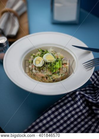 Traditional Salad Olivier. Christmas And New Year Food. White Plat With Fork And Knife On Blue Backg