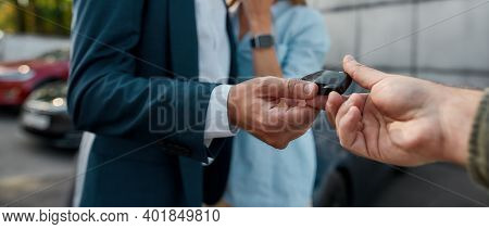 Close Up View Of Car Keys Given To Businessman By Sales Manager In Luxury Auto Showroom, Panorama. C