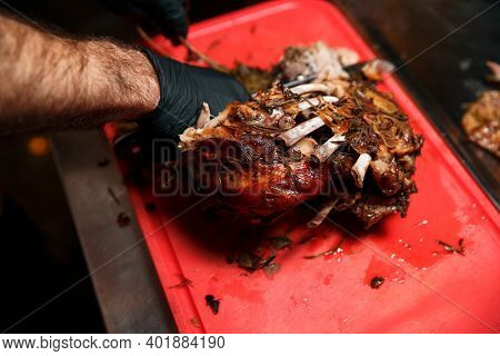 Chev Cuts Juicy Cooked Meat, Separating The Meat From The Bone With A Knife.