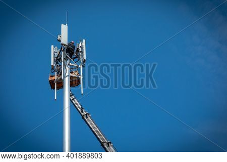 Workers Install Cellular Base Station With Transmitters 3g, 4g, 5g And Antennas On Cell Tower On Bac
