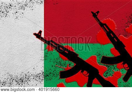 Madagascar Flag And Two Black Ak-47 Rifles In Red Blood. Concept For Terror Attack Or Military Opera