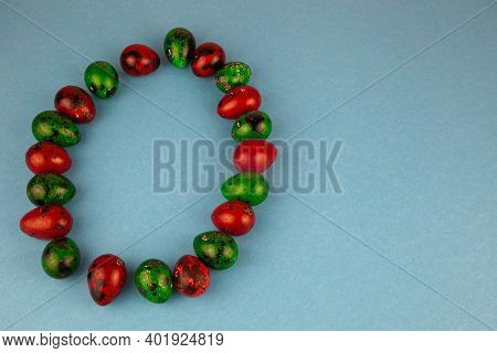 Multicolored Quail Eggs Green And Red On A Blue Background With Place For Text. Happy Easter Postcar