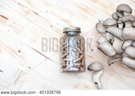 A Bottle Of Mushroom Supplement Capsules And Fresh Mushrooms On A Wooden Table. Antioxidant And Deto