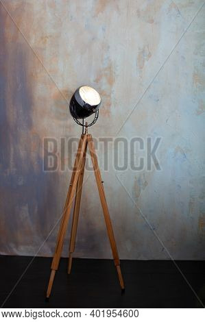 Stylish Lamp On Tripod In Room. Tripod Light Projector. Decorative Light Projector Stands Against A 
